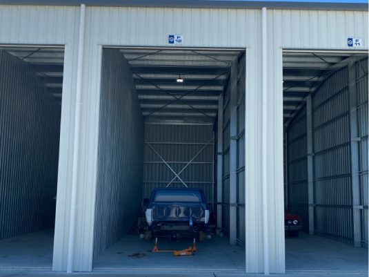 three open storage units for cars with cars inside